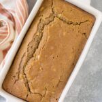 Apple cider bread in a white baking loaf pan on a grey background