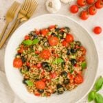 Easy Farro Salad in a white bowl with tomatoes and fresh herbs on the side.