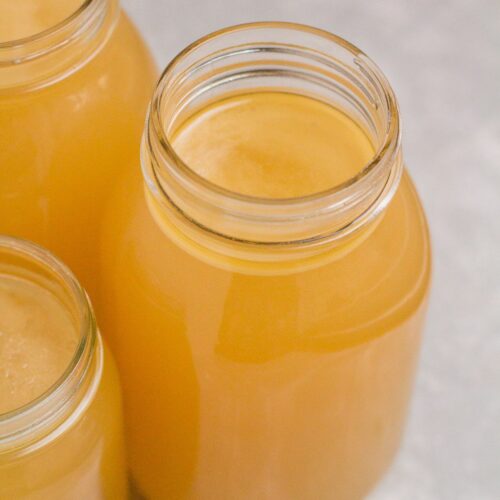 Instant Pot Bone Broth in glass jars on a grey background.