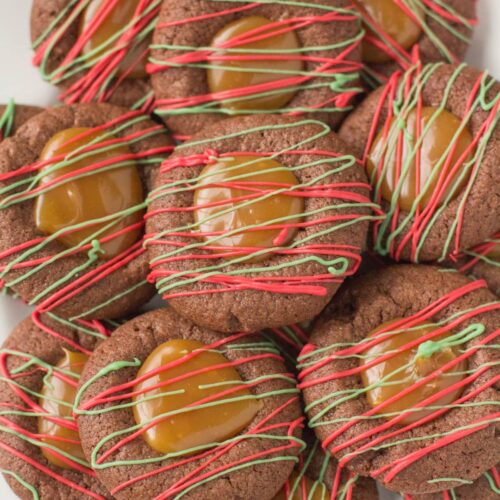 Chocolate Caramel Thumbprint Cookies drizzled with christmas colored chocolate on a white plate