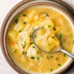Instant Pot Potato Soup in a brown rimmed bowl with a spoon taking a scoop