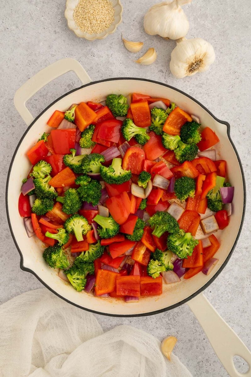 Chopped vegetables being cooked in a pan for sweet and sour chicken.