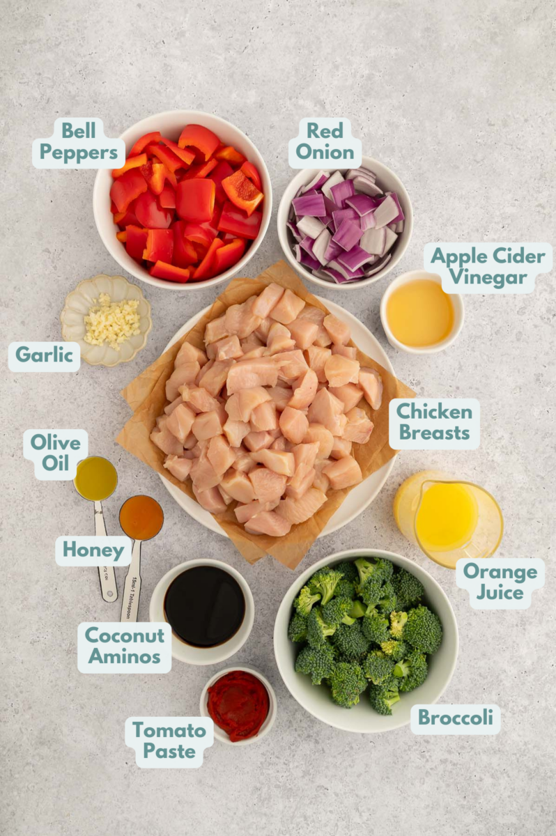 Labeled ingredients for Healthy Sweet and Sour Chicken in small white bowls on a grey background.