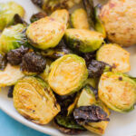 Buffalo Brussels Sprouts on a white plate on a bright blue background