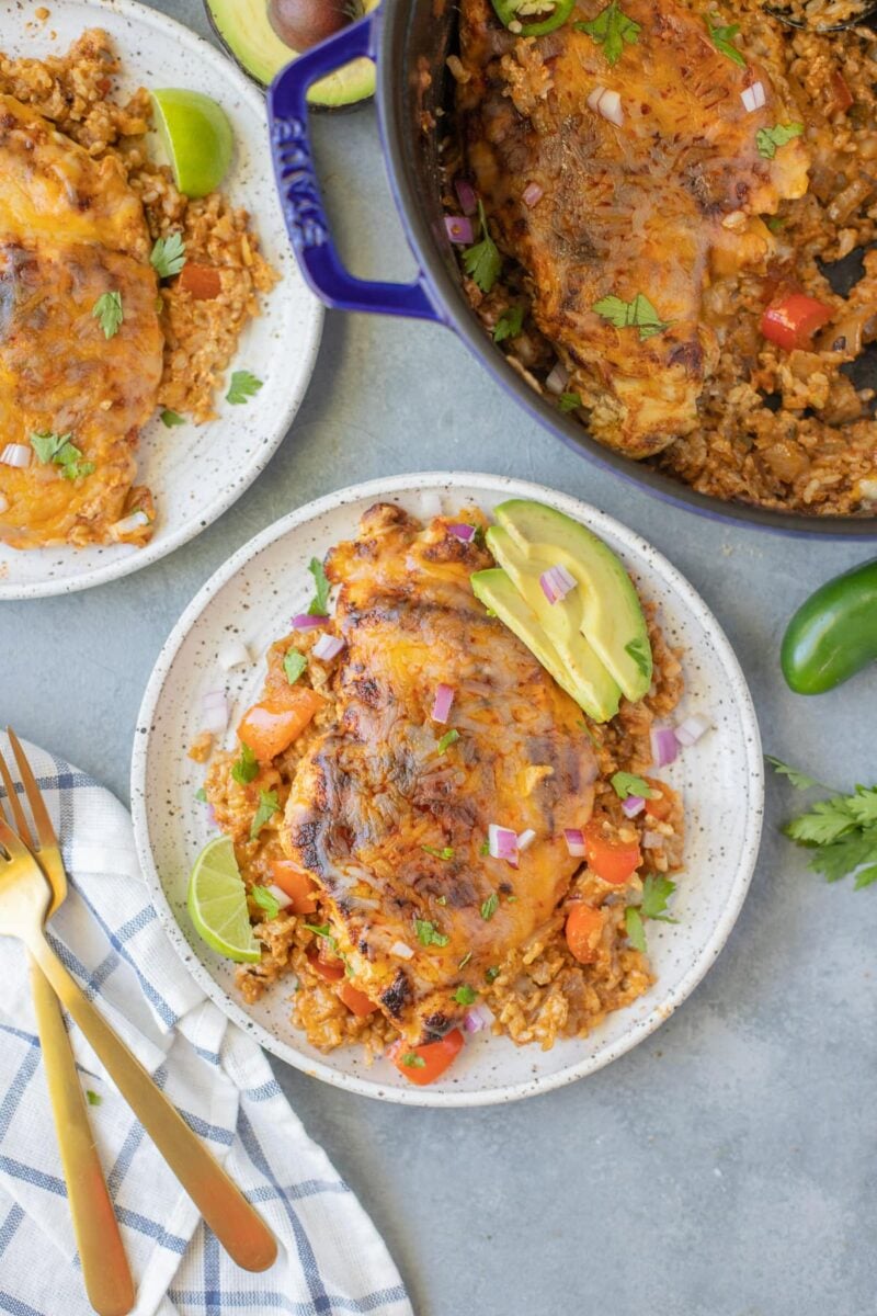 An overhead image of chicken fajita casserole on a white dish on a grey background with other dishes and casserole off to the side.