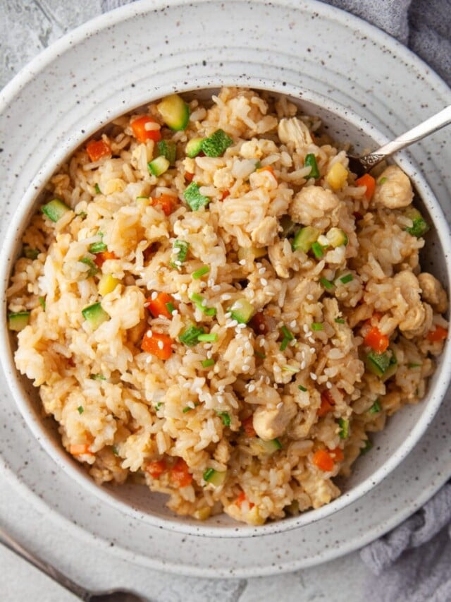 An close up shot of a bowl of instant pot chicken fried rice with a fork in the bowl