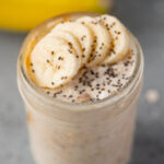 A mason jar with banana overnight oats with sliced bananas and chia seeds on top