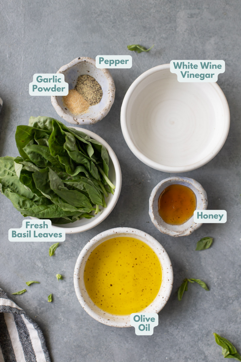 Ingredients for Basil Salad Dressing in small white bowls on a grey background