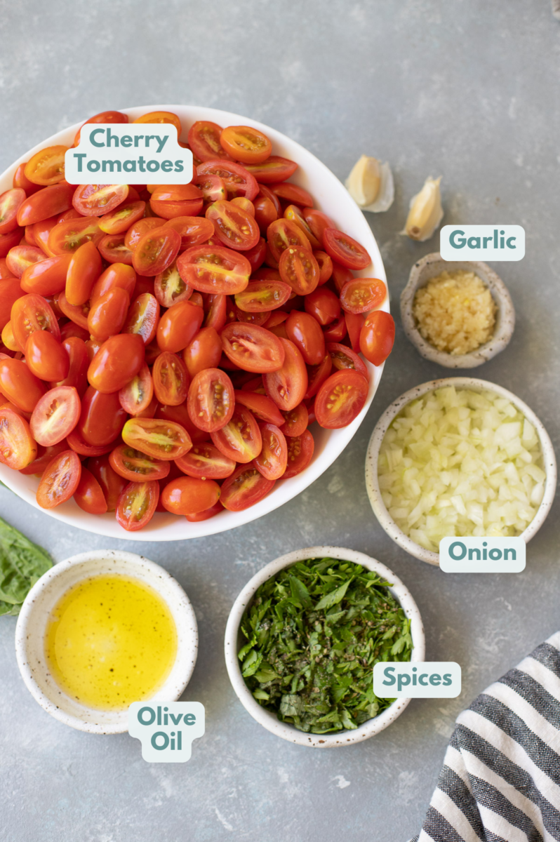 Ingredients for spaghetti sauce with fresh tomatoes in white bowls: olive oil, minced garlic, onion, tomatoes, fresh basil, fresh parsley, dried oregano, salt + pepper