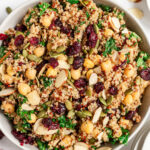 An overhead shot of a bowl of kale quinoa salad on a grey background