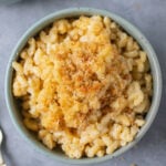 An overhead shot of a blue bowl of healthy mac and cheese on a grey background