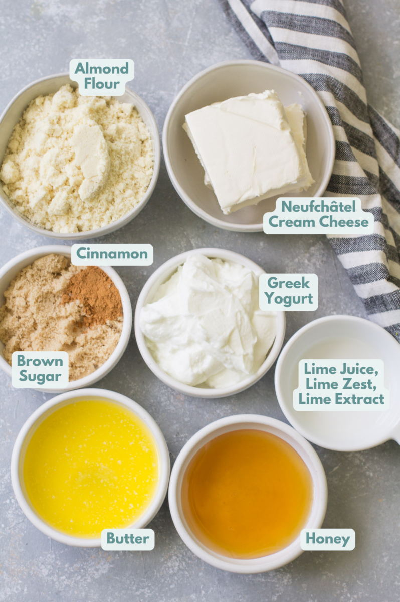 Ingredients for healthy lime cheesecakes in white bowls: Bob’s Red Mill Almond Flour, brown sugar, cinnamon, butter, Neufchâtel cream cheese, nonfat greek yogurt, honey, lime zest/lime juice, lime extract
