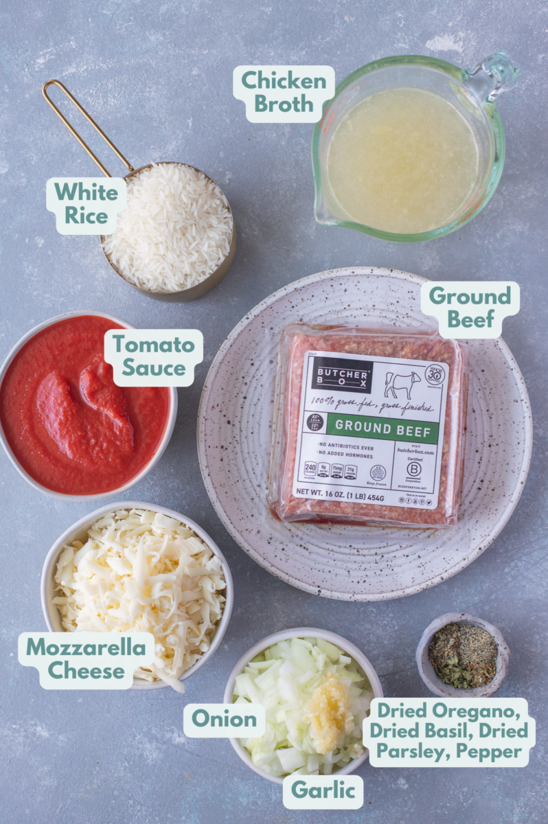 Ingredients for hamburger casserole in white bowls: ground beef, onion, garlic, jasmine rice, chicken broth, tomato sauce, mozzarella cheese, dried basil, dried parsley, dried oregano, pepper
