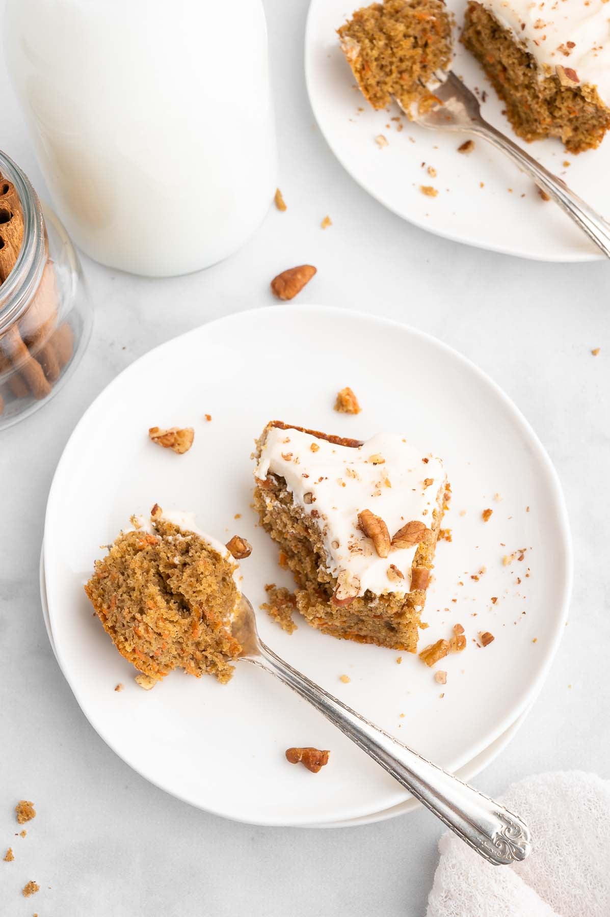 Two plates with partially eaten servings of frosted cake, viewed from overhead.