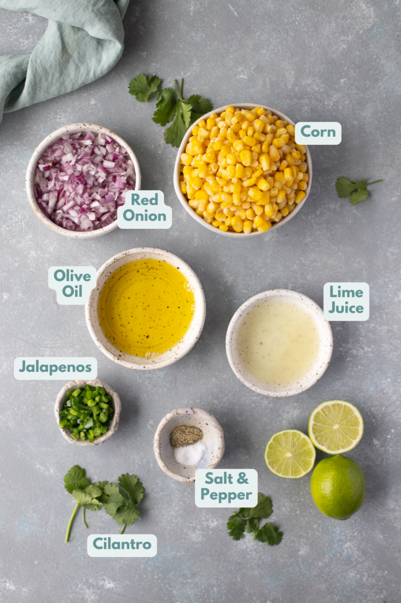 Ingredients for corn salsa in white bowls on a grey background