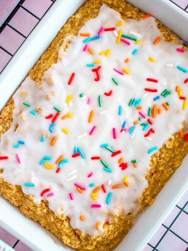 An overhead shot of baked oats in a white baking dish topped with white frosting and sprinkles