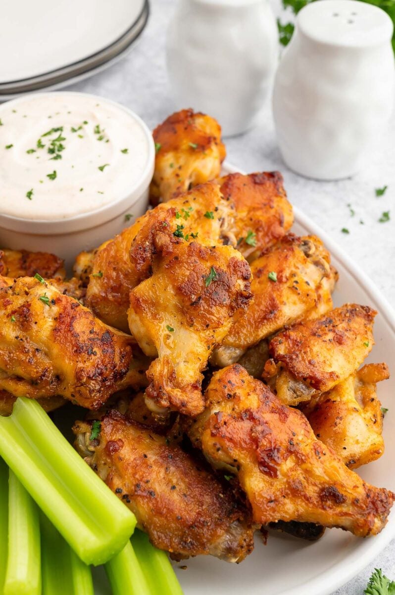 Baked Chicken Wings on a plate with celery and a container of ranch dip on the side.