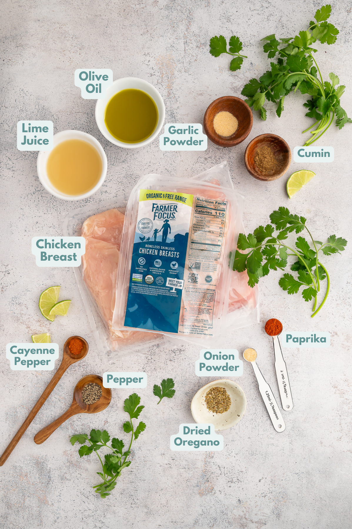 Ingredients for chili lime chicken marinade in small bowls surrounding a package of uncooked boneless, skinless chicken breasts.