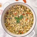 Tuscan Chicken Orzo in a dutch oven with spinach and sun dried tomatoes on the side.