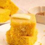 Two pieces of cornbread stacked on each other with a pat of butter on top.