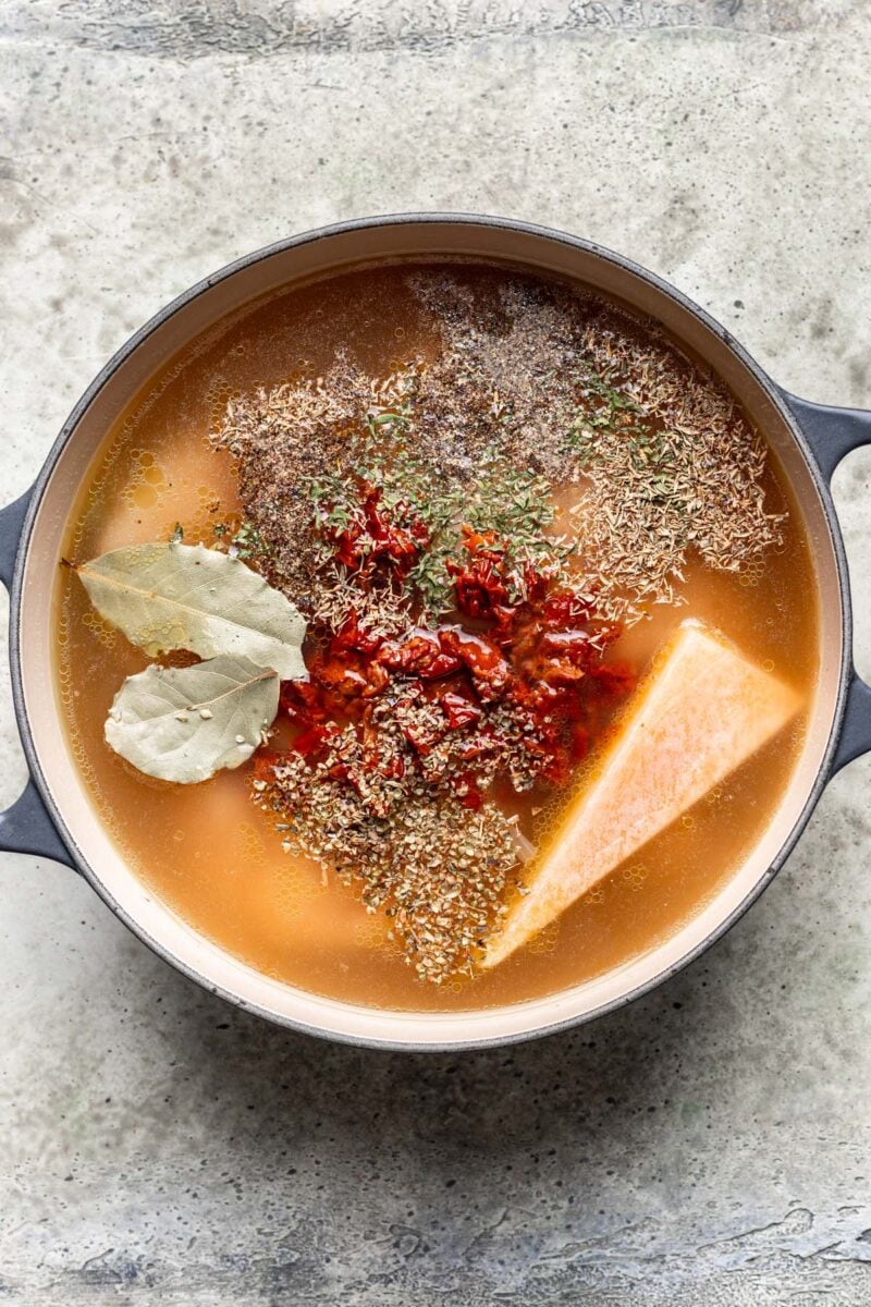 Ingredients for tuscan chicken soup in a dutch oven before cooking and before stirring together. 