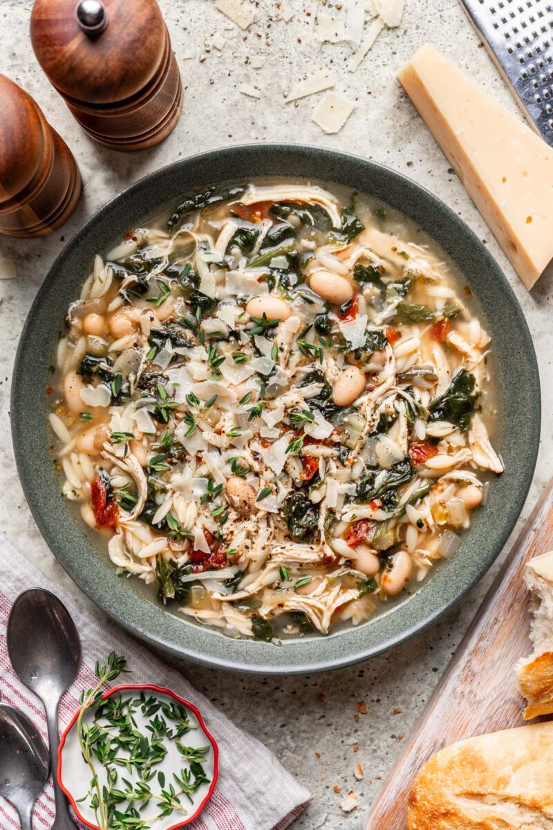 Tuscan Chicken Soup in a grey bowl and parmesan cheese rind on the side.