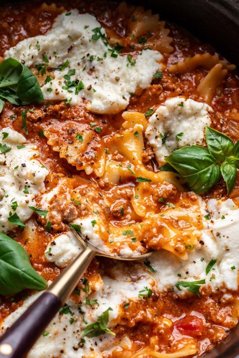 A close up of one pot lasagna skillet with a spoon taking a scoop out of it. 