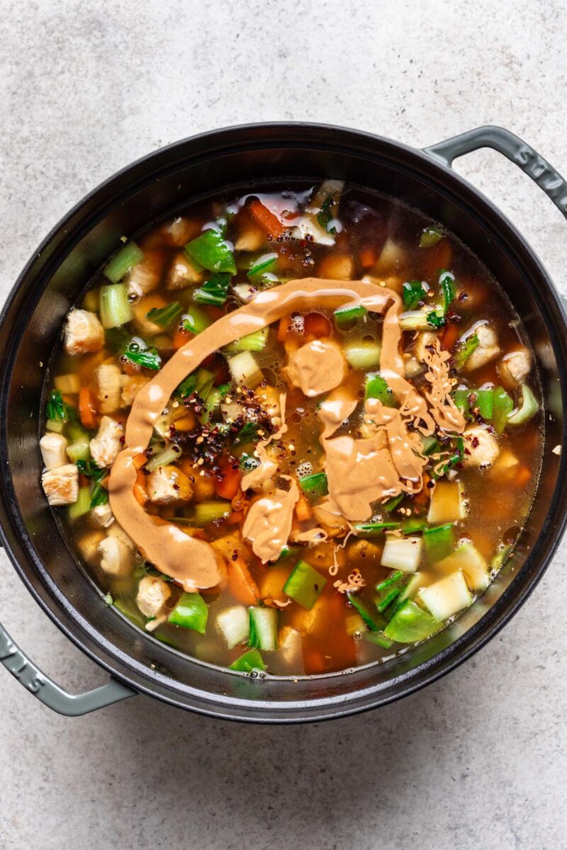 Chicken and rice noodle soup in a large pot before fully mixed together and not fully cooked.