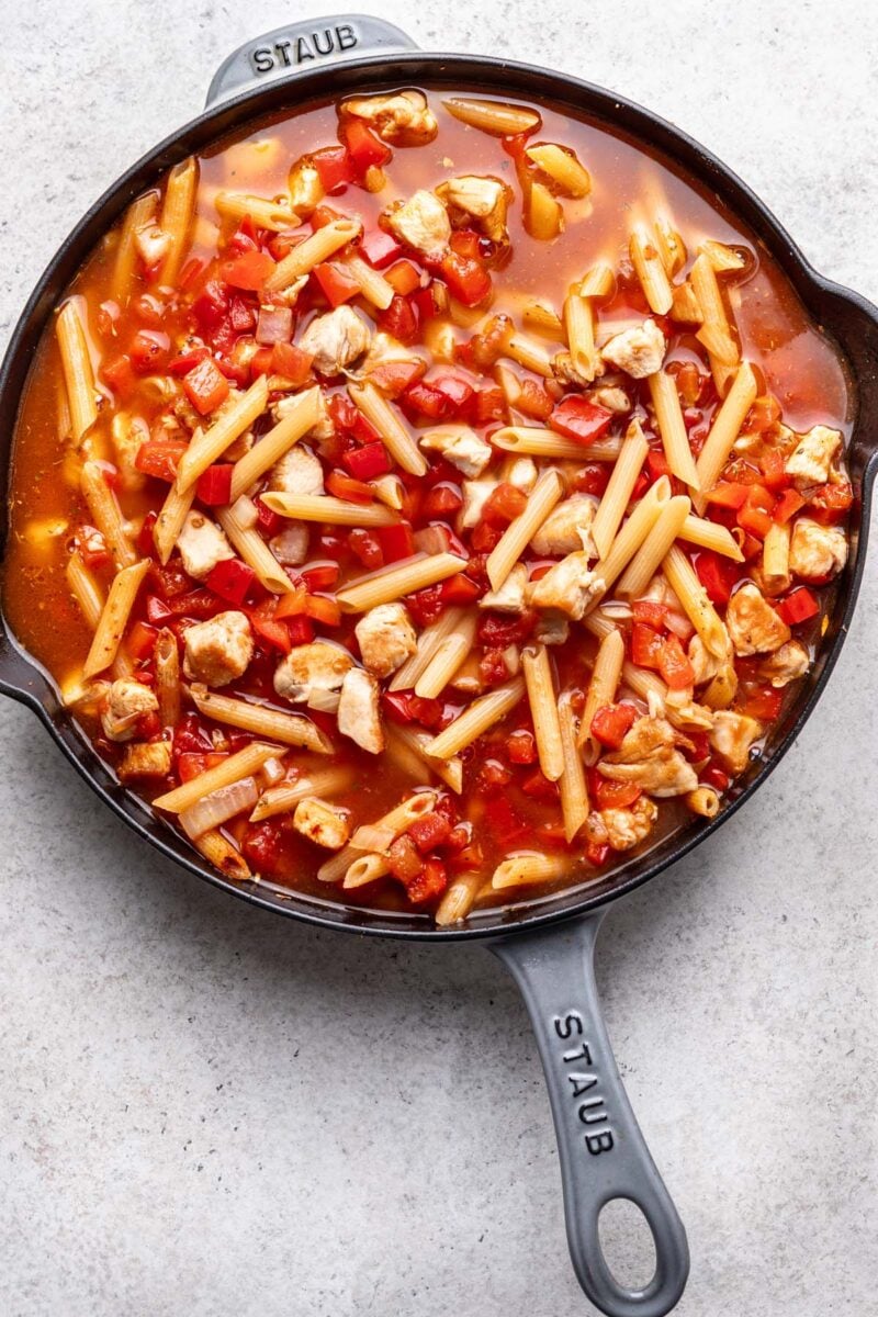 Uncooked cajun chicken pasta in a cast iron skillet. 