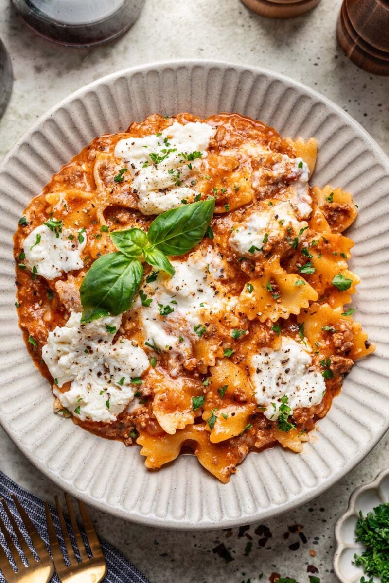 A white plate with one pot lasagna topped with fresh basil.