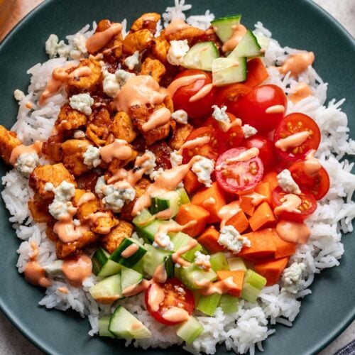 Buffalo Chicken Rice with veggies topped with sauce in a bowl.