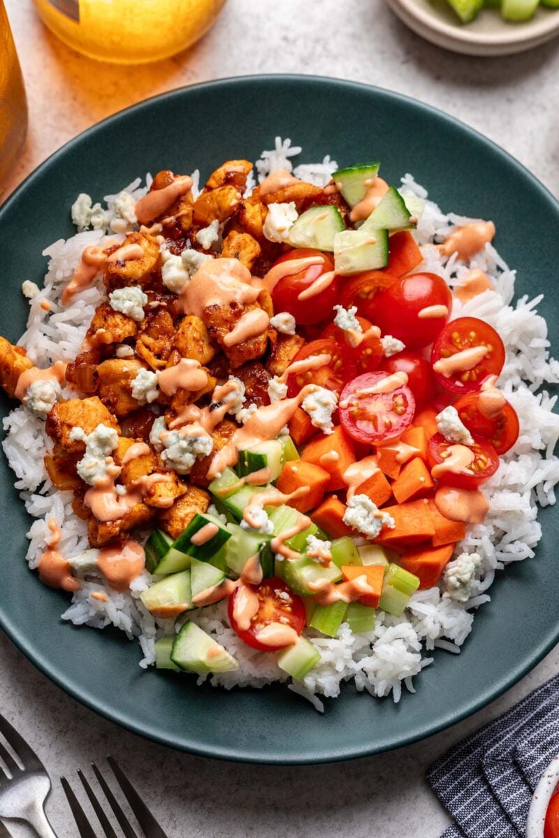 Buffalo Chicken Rice with veggies topped with sauce in a bowl.