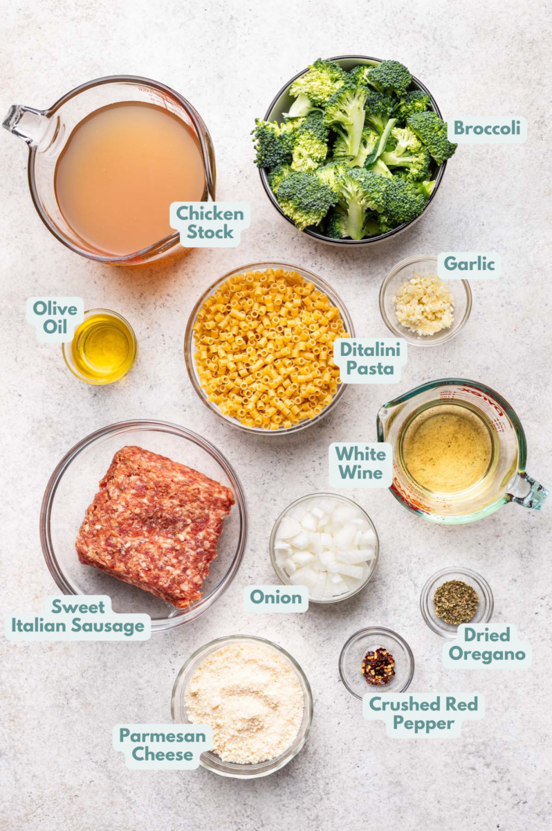 Labeled sausage broccoli pasta Ingredients in bowls and measuring cups on a counter.