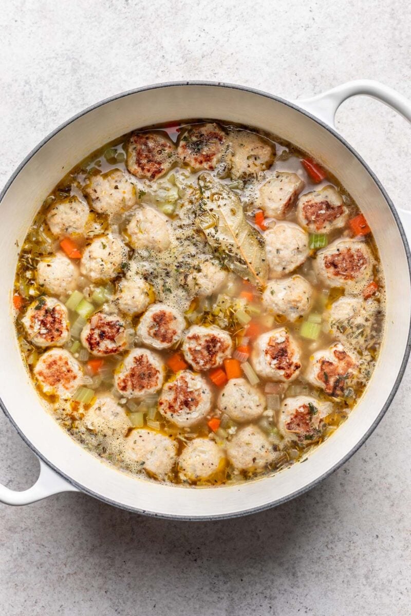 Chicken Meatball Soup in a large dutch oven before being fully cooked and before spinach is added.