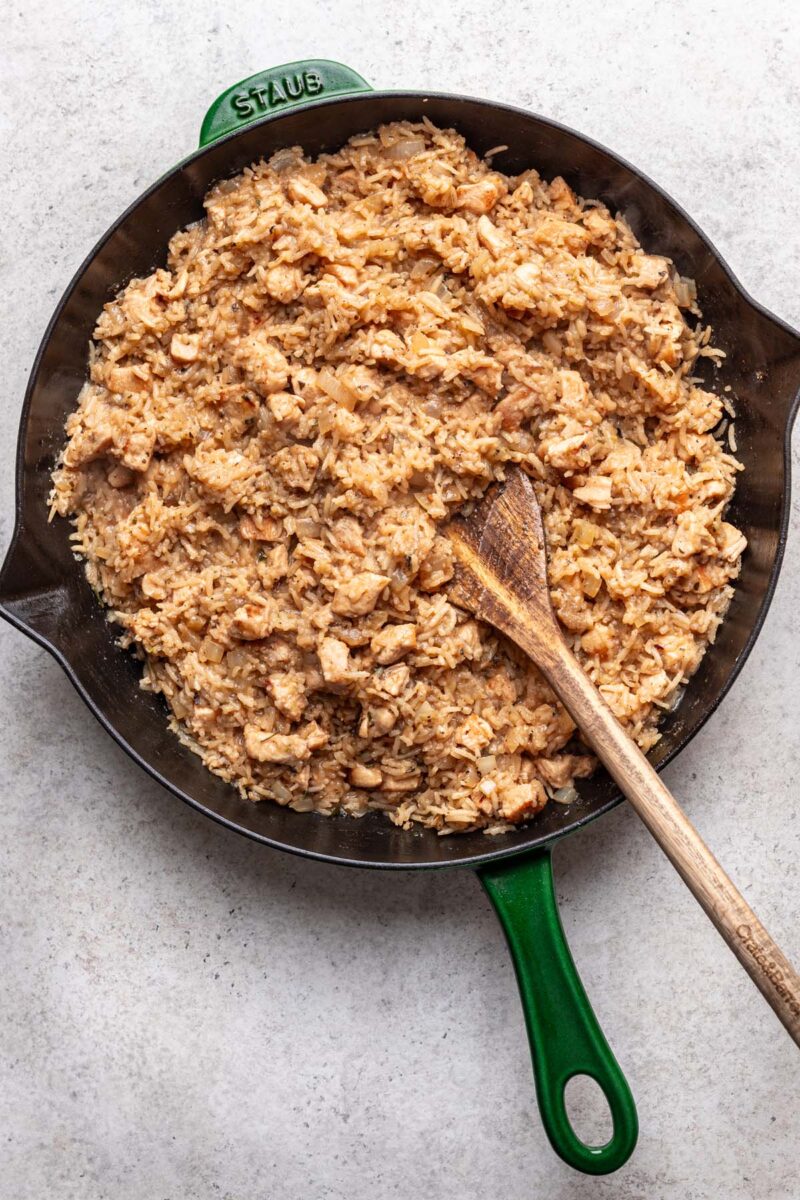 Lemon Chicken and Rice in a cast iron skillet with a wooden spoon in it. 