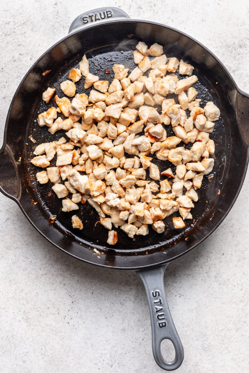 Chicken pieces browned in a cast iron skillet. 