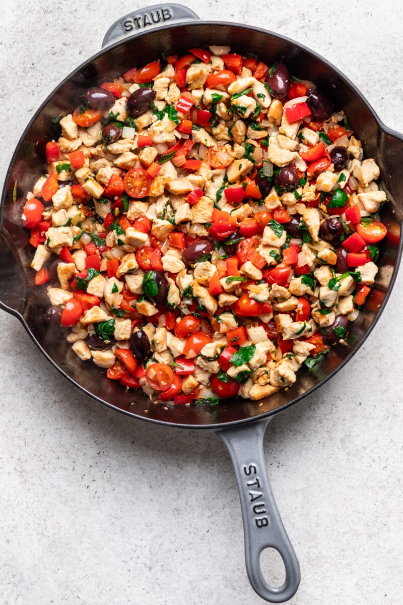 Greek veggies and chicken in a cast iron skillet.