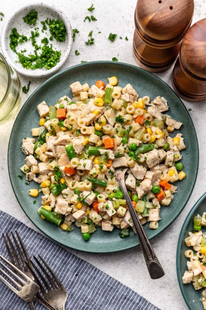 Chicken Pot Pie Pasta on a plate with a fork in it with more herbs and forks on the side.
