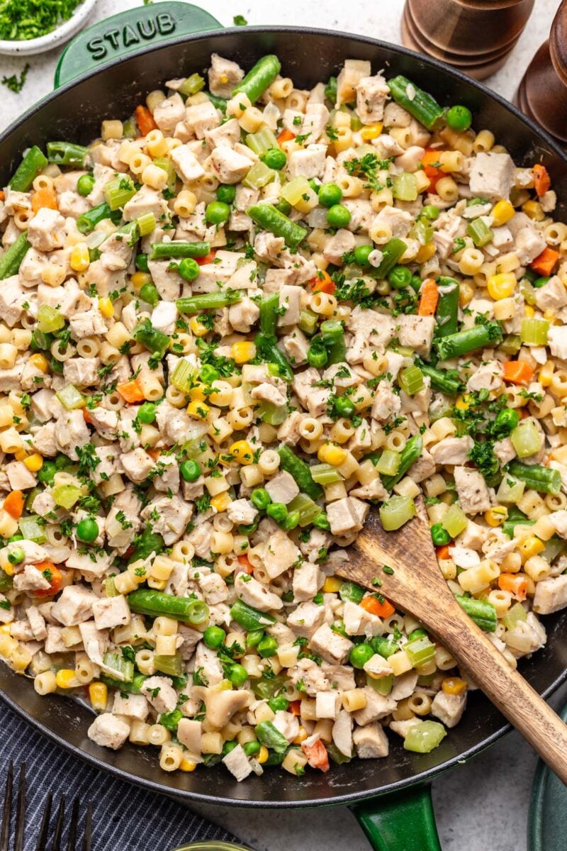 Chicken Pot Pie Pasta in a skillet with a wooden spoon in it. 
