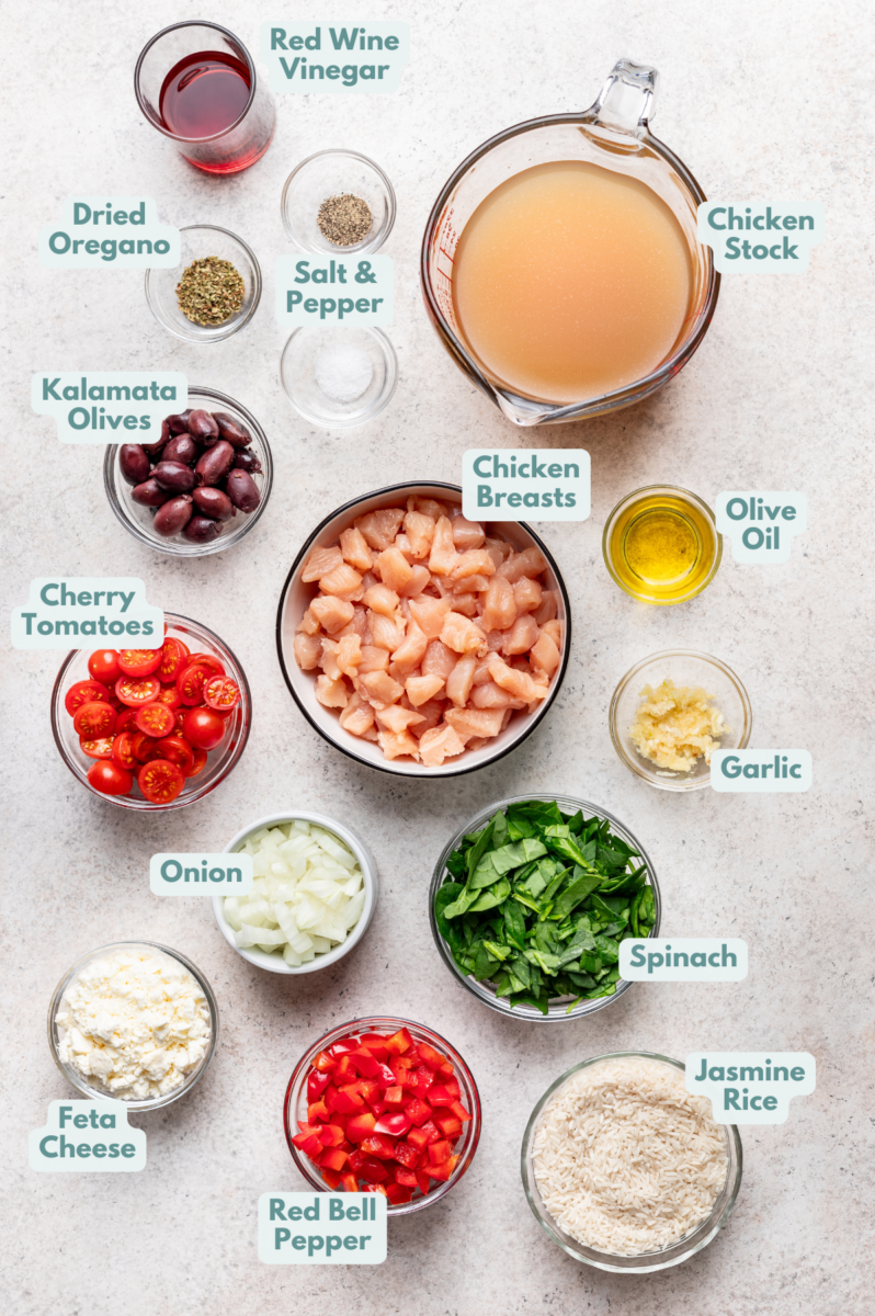 Labeled greek chicken and rice ingredients in bowls and measuring cups on a counter.