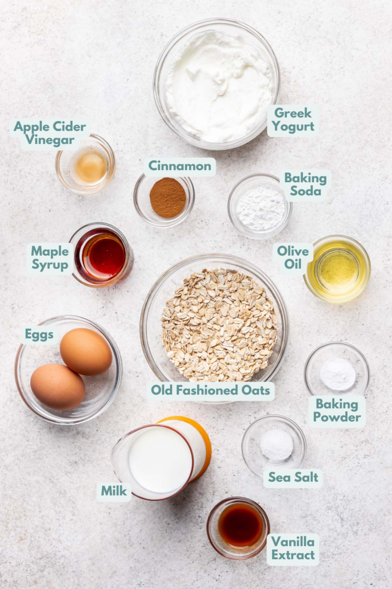 Labeled oat flour pancakes ingredients in bowls and measuring cups on a counter.
