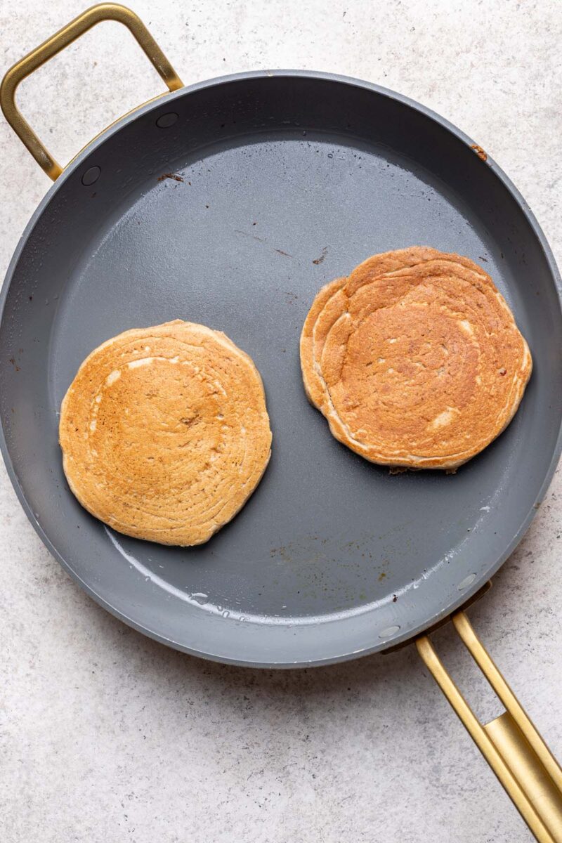 Two oat flour pancakes in a skillet. 