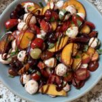 Peach Caprese Salad drizzled with balsamic glaze in a blue bowl