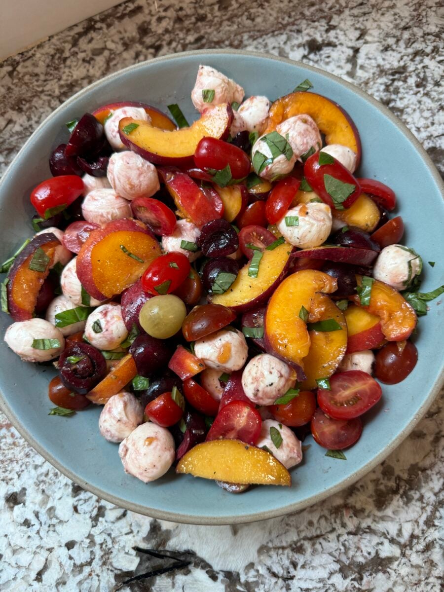 Peach caprese salad before being dressed in a blue bowl