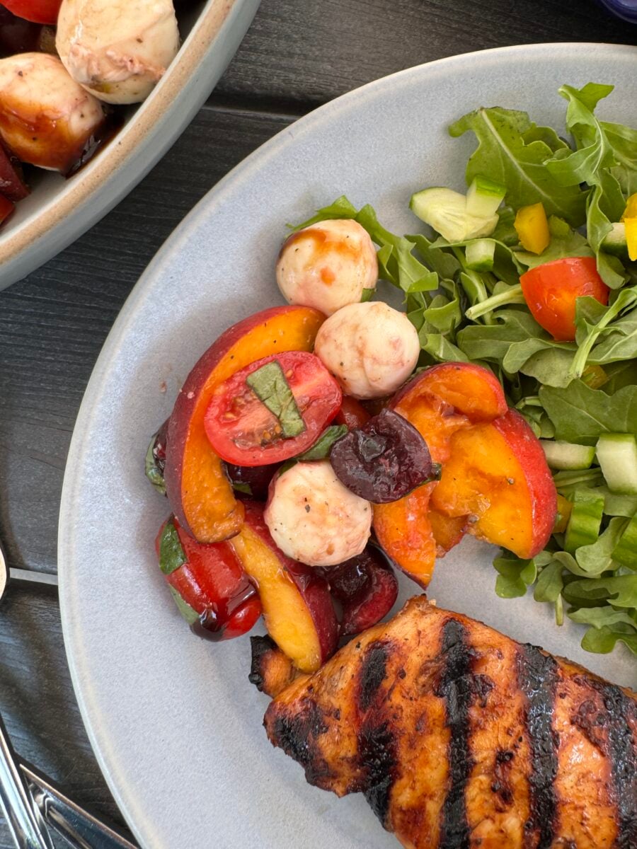 A close up of peach caprese salad on a blue plate.