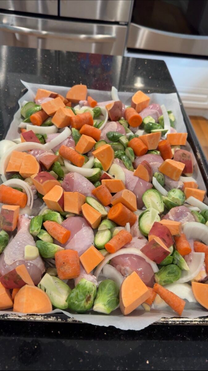 sweet potatoes, onions, and vegetables being added to a sheet pan